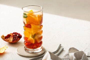 Glass of infused water with different sliced fruits on white table