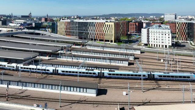 Pendolino, the fastest express train in Poland, leaving Krakow Main station with a big parking lot on the roof. Cityscape with far view of Wawel, st. Mary church and town hall tower. Aerial video