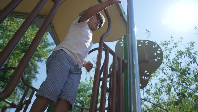 Kid slides down from metal pole at playground park during beautiful sunny day