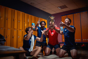 Group of young football players celebrating golden trophy together in the dressing room.