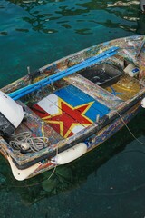 Fototapeta na wymiar Vertical shot of a wooden boat with a red star and colorful stripes painted on the floor