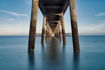 Coastal scene featuring a pier extending out into the horizon, with numerous concrete pillars