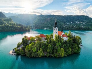 Church and Castle in Lake Bled, Slovenia with mountains and lush trees in the background