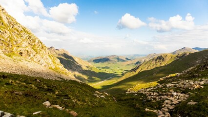 Peak of rocky mountain covered with green grass with blue sky in the background