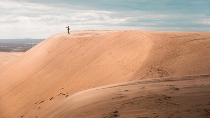 Person in a distance on the top of Rabjerg Mile sand dunes on the horizon in Skagen, Denmark