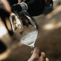 White wine poured into a glass by a waiter at a tasting in a restaurant. - 606766350