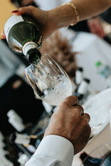 White wine poured into a glass by a waiter at a tasting in a restaurant. - 606766353