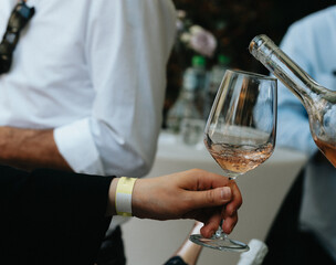 Rose wine poured into a glass by a waiter at a tasting in a restaurant. - 606766384