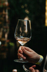 Rose wine poured into a glass by a waiter at a tasting in a restaurant. - 606766397