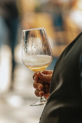 White wine poured into a glass by a waiter at a tasting in a restaurant. - 606766522