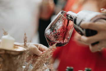 Red wine poured into a glass by a waiter at a tasting in a restaurant. - 606766574
