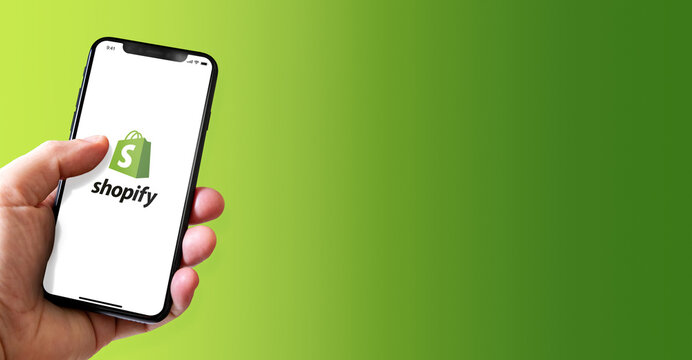 Hand holding iphone smartphone with Shopify logo, Paris, France