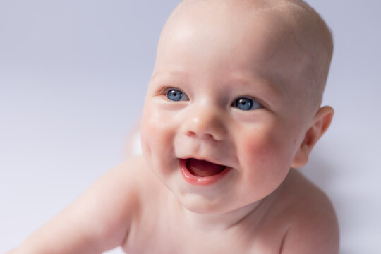 portrait of a cute baby 5 months old on a white background in the studio, smiling looking into the frame. Baby's health, newborn baby, space for text