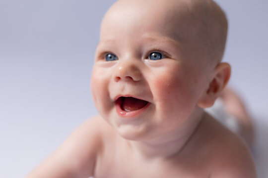 portrait of a cute baby 5 months old on a white background in the studio, smiling looking into the frame. Baby's health, newborn baby, space for text