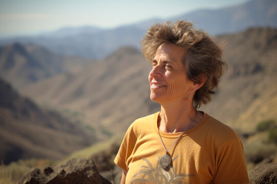Group portrait photography of a woman in her 50s practicing mindfulness sophrology relaxation & stress-reduction wearing a fun graphic tee against a mountain valley or canyon background