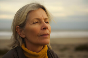 Portrait of a mature woman on the beach at sunset in autumn