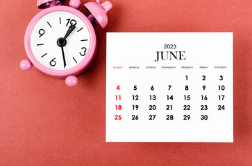 The June 2023 Monthly calendar year with alarm clock on red and black background.