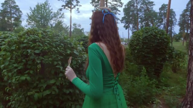 A woman in a fairy dress paints trees with paint.