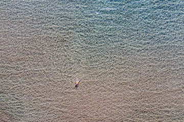 Woman swims in transparent Aegean sea aerial drone view. Summer leisure Greece Cyclades island.
