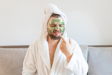 funny bearded man applying green mask for skin care