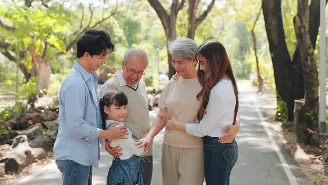 Happy Multi-generation Asian family smiling and hugging in the park, Big family standing in the public garden concept