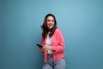brunette young woman with shoulder-length hair in a pink shirt sits in the internet online from the phone and isolated on a solid background