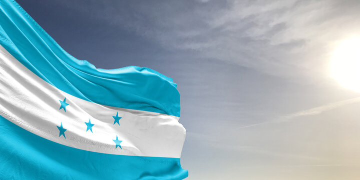 Honduras national flag cloth fabric waving on beautiful grey sky Background.