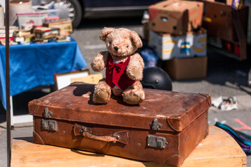 Teddybär sitzt auf einen alten Koffer auf einem Flohmarkt