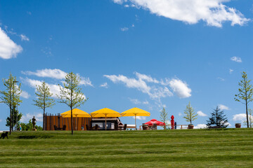 Gastronomie mit Sonnenschirm, Tisch Stühlen an einem See mit blauen Wolken in der Wilhelminenaue Bayreuth