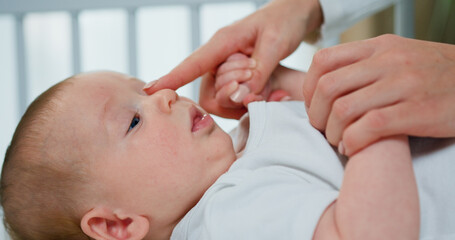 Close up of cute little toddler on mother's hands. Mother caresses and touches of her cute newborn...