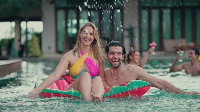 Happy man and woman are playing in the swimming pool of a holiday resort. Outdoors travel holiday vacation trip at private pool villa concept