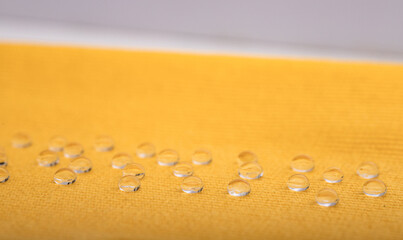 water repellent fabric, yellow fabric does not absorb water drops. Laboratory water repellent test. Selective focus.