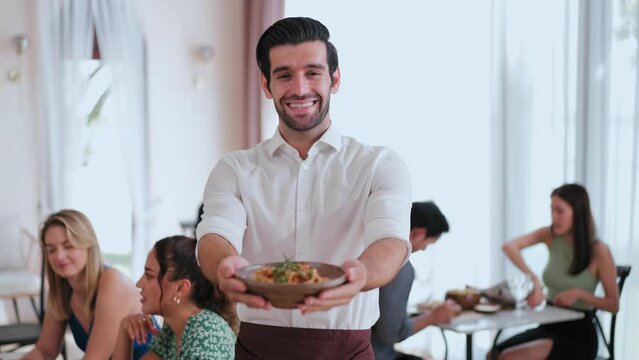 Waiter man Standing smiling and handing over the bowl of food looking at the camera in restaurant, Service Food and Restaurant