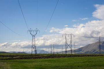High voltage power supply pylons in the green field, tall overhead power supply poles, transmission of electricity