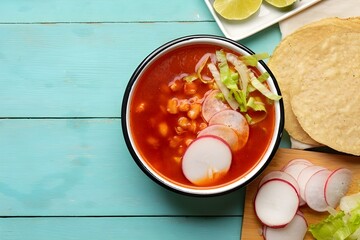 Best Mexican pozole soup on wooden background,  lettuce, radish, onion, lime and chilli