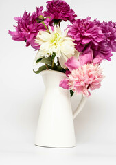 Blooming pink peonies in a white ceramic vase on a white background. Floral arrangement