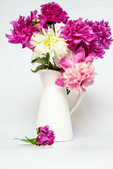 Blooming pink peonies in a white ceramic vase on a white background. Floral arrangement