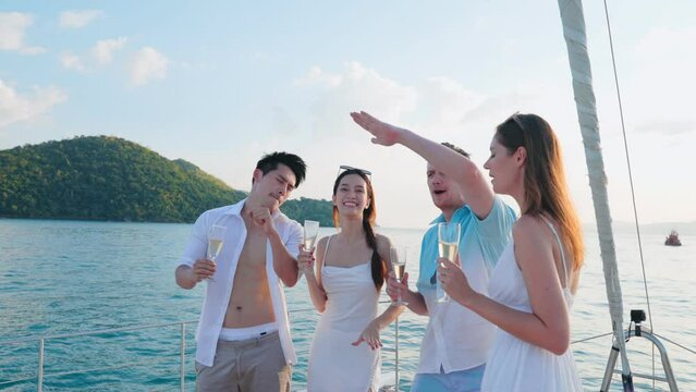 Group of young diverse people drinking wine and champagne while having sail boat party. Group of men and women friends enjoy party and having fun together while yacht sailing at sunset