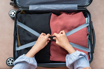 Closeup of a woman preparing and putting her clothes in a suitcase, A woman packing luggage in a...