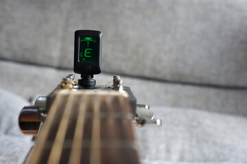Selected focus photo of tuning guitar process with digital guitar tuner.            