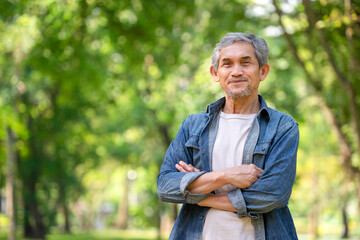 happy senior man smile while standing in the forest park,positive healthy older adult walking in summer park,concept active old people lifestyle,health benefit in nature,wellness,wellbeing,longevity
