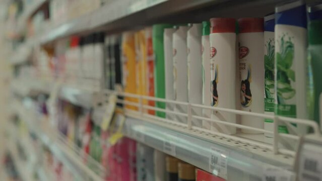 Female hands choosing shampoo in the supermarket. Close up.