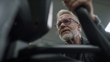 Senior man in his 60s cycling on a bike machine in the gym