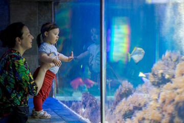 Fototapeta na wymiar Little girl with her mother looking at the aquarium