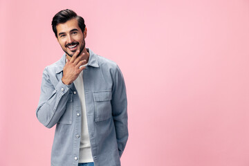Obraz premium Portrait of a stylish brunette man with a beard beautiful smile on a pink background in a white T-shirt and jeans smile and joyful emotion on his face, copy space