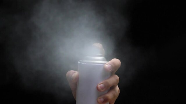 Slow motion speed closeup scene in front view of aerosol can when spraying, white color spray isolated on black background, damage ozone made greenhouse effect problem cause of global warming. 