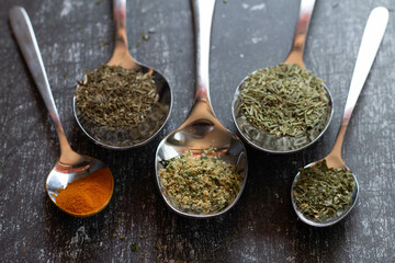 Spoons with spices and herbs on a black background. Food and cuisine ingredients.