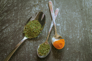 Spoons with spices and herbs on a black background. Food and cuisine ingredients.