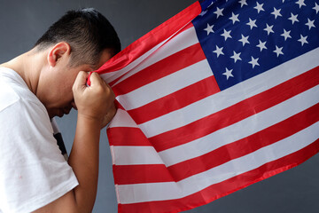 Close-up of young man holding United States of America USA national flag showing gratitude with copy space. 