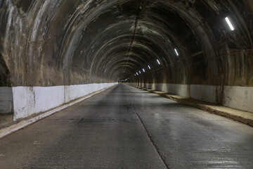 Fototapeta na wymiar Tunnel with road inside mountain with arch dam.
